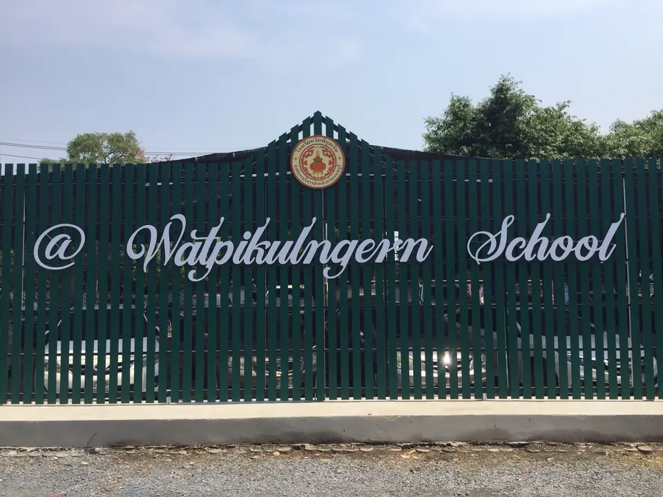 ตัวอย่างงานงานเลเซอร์ตัด: ตัวอักษรชื่อโรงเรียนกับตราโรงเรียน ติดบนรั้วสีเขียว